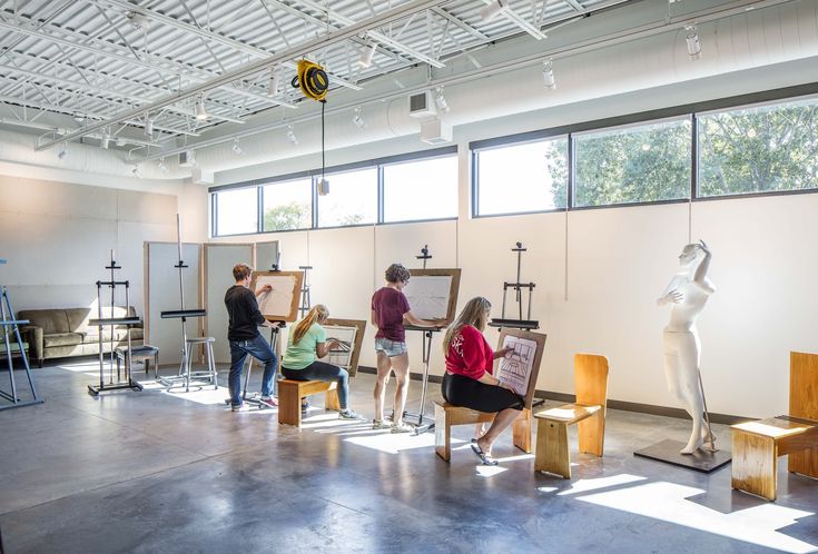 people standing around in an art studio working on some paintings and sculptures with easels