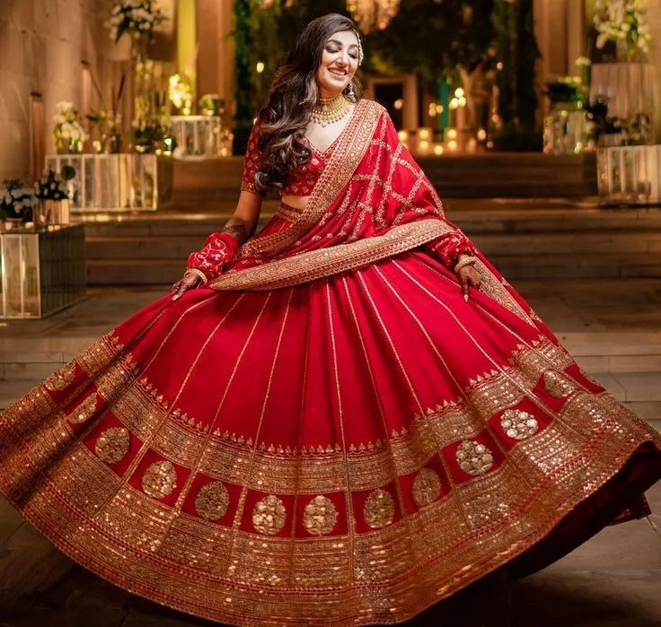 a woman in a red and gold lehenga