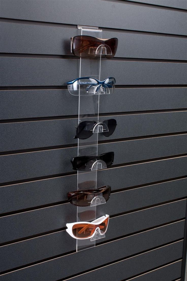 several pairs of sunglasses are hanging on a wall in front of a pair of glasses