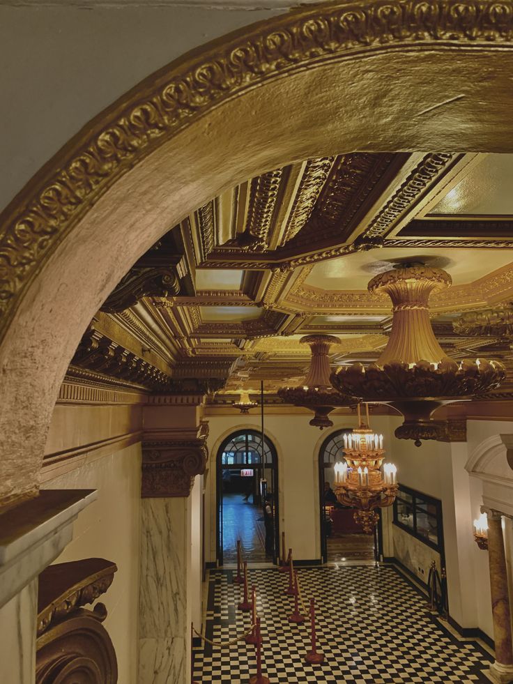 an ornate hallway with chandeliers and checkered flooring