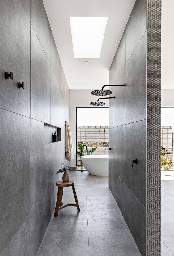 a modern bathroom with concrete walls and flooring, along with a skylight above the bathtub