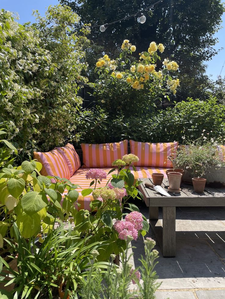 a couch sitting on top of a wooden table next to flowers and plants in pots