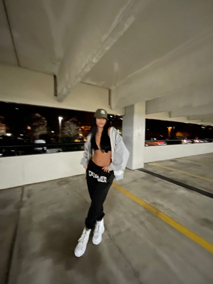 a woman standing in an empty parking garage with her hand on her hip and looking at the camera