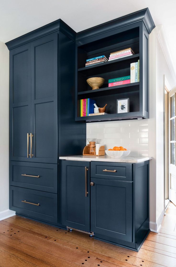 a kitchen with dark blue cabinets and white counter tops, gold pulls on the cupboards