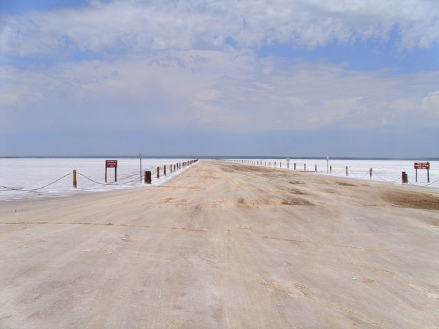 a dirt road that is next to the ocean with no cars or people on it