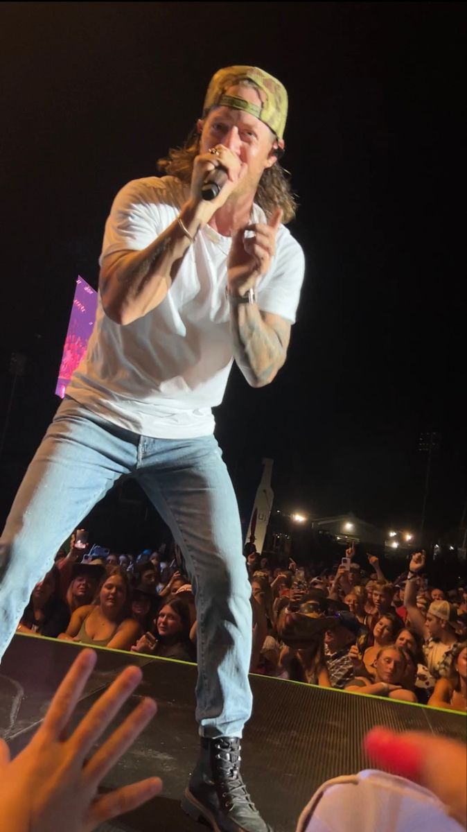 a man standing on top of a stage holding a microphone in front of an audience