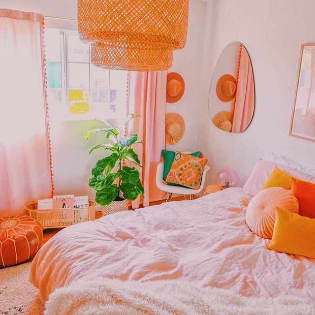 a bedroom decorated in pink and orange with wicker lamps hanging from the ceiling above the bed