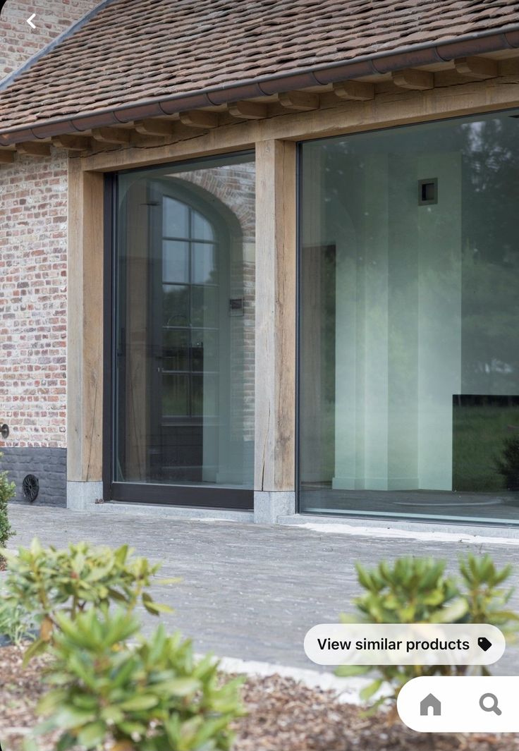 a brick building with glass doors and plants in the foreground