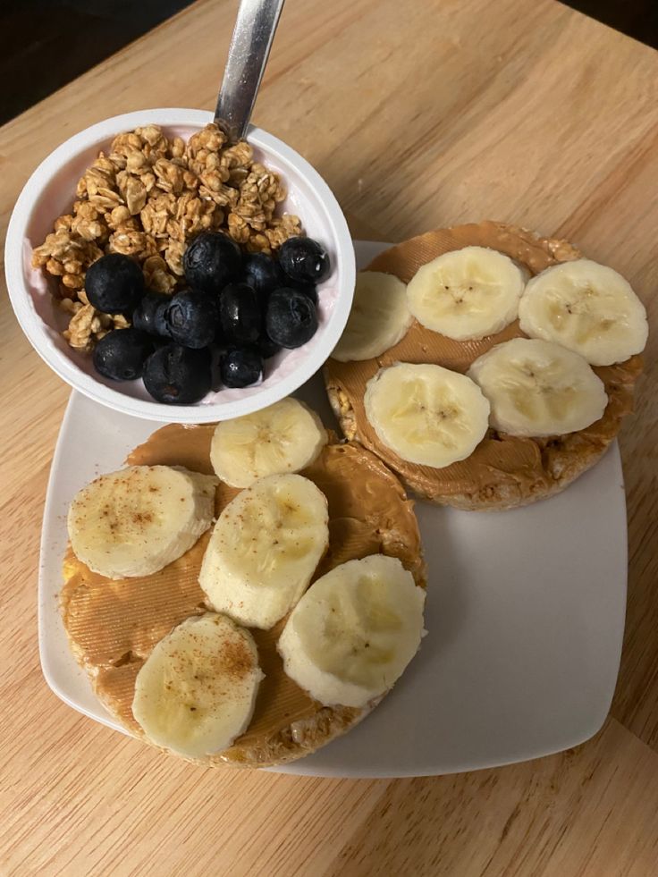 the breakfast is ready to be eaten on the table for everyone to eat it has bananas, blueberries and granola