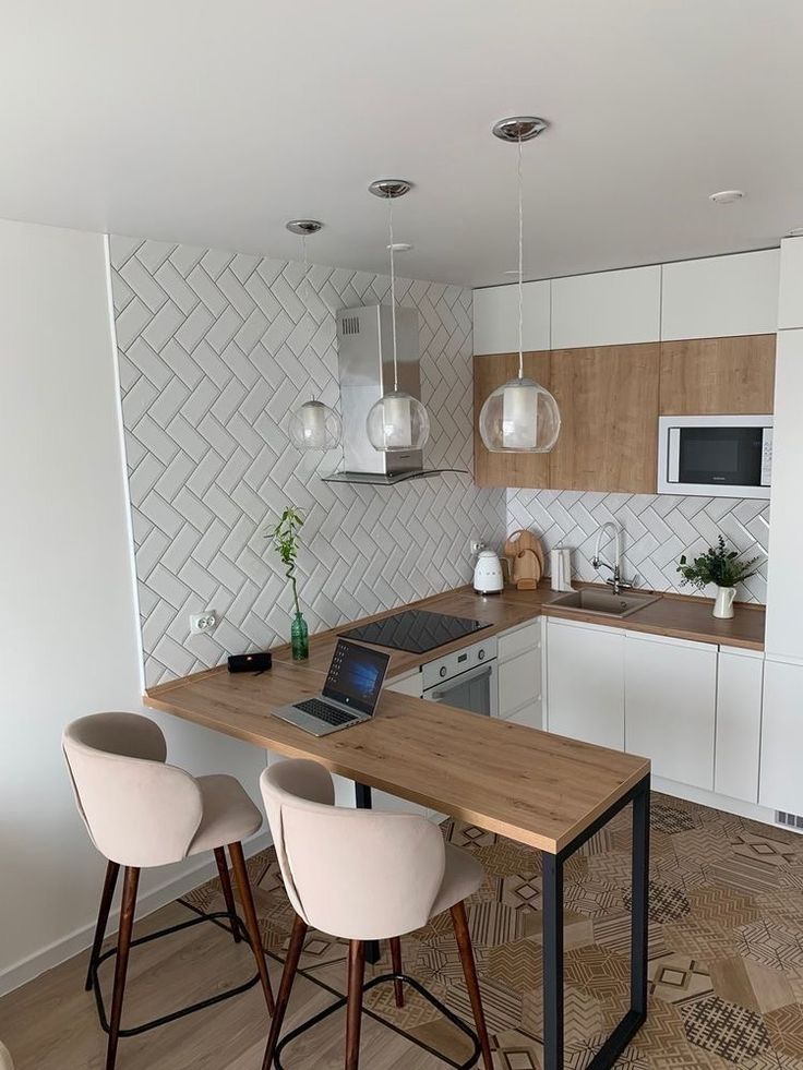 a kitchen with white cabinets and wooden counter tops next to a laptop on a table