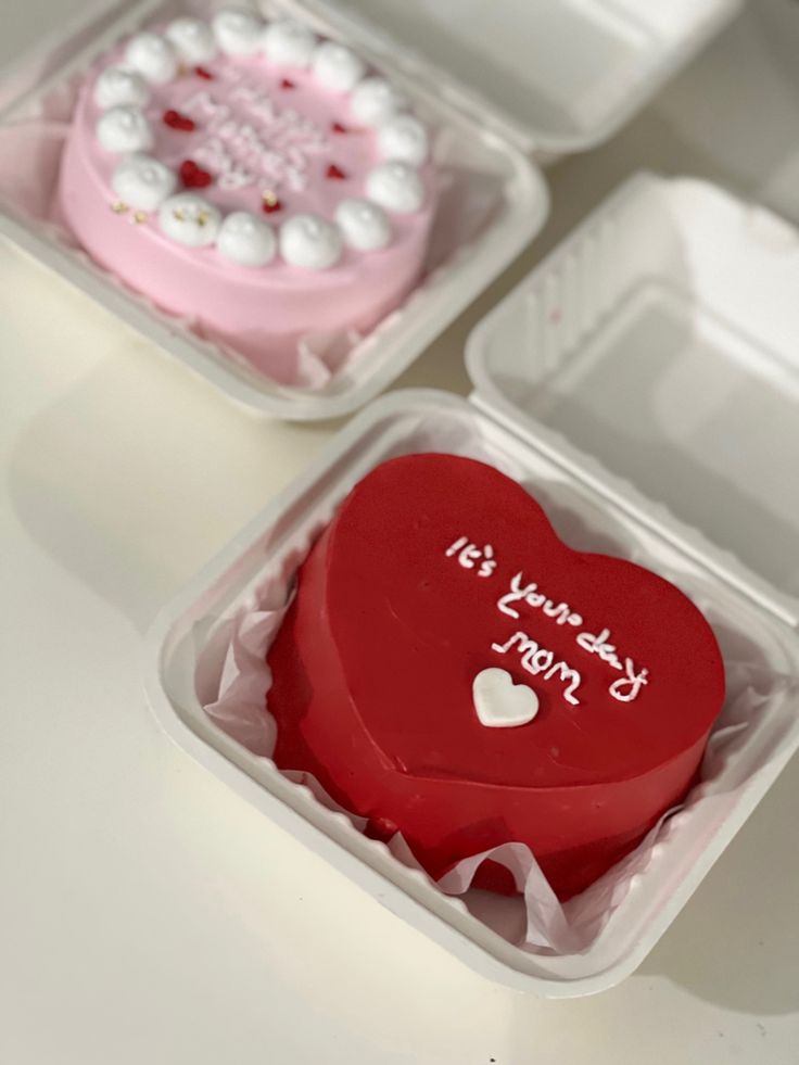 two heart shaped cakes in plastic containers with writing on them