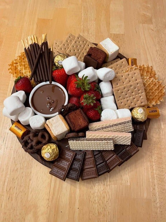 a platter filled with chocolate, marshmallows, strawberries and crackers