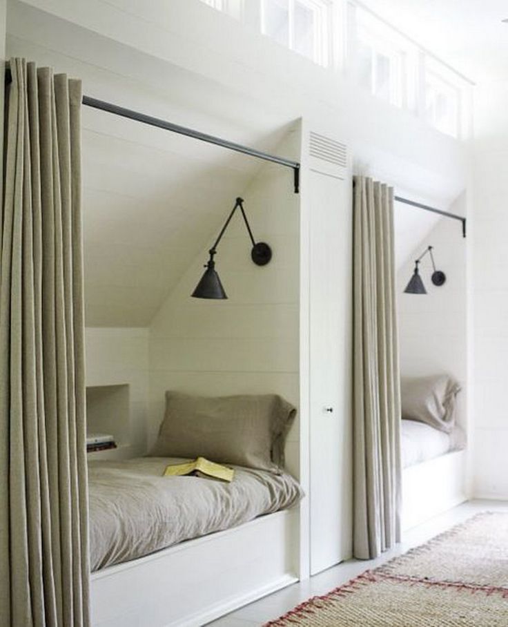 an attic bedroom with two beds and hanging lights on the wall above them, along with a rug