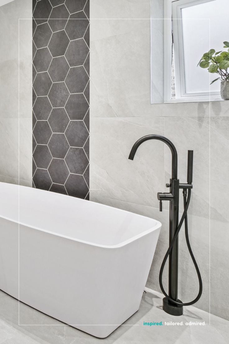 a white bath tub sitting next to a window in a bathroom with tiled walls and floor