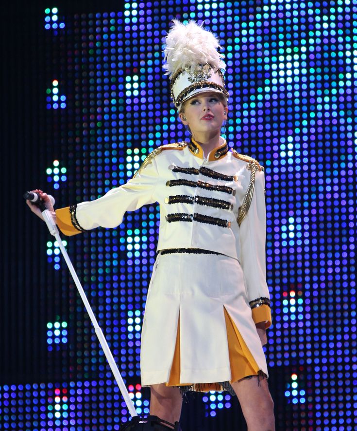 a woman in a costume on stage with a cane and headdress, holding a stick