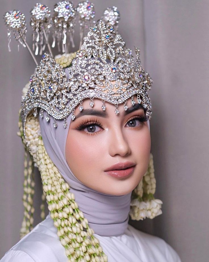 a woman wearing a white hijab and headpiece with pearls on it's sides