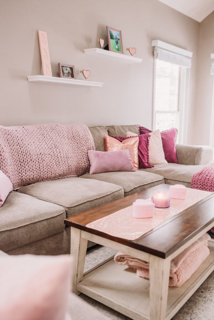 a living room filled with lots of furniture and pink pillows on top of the couch