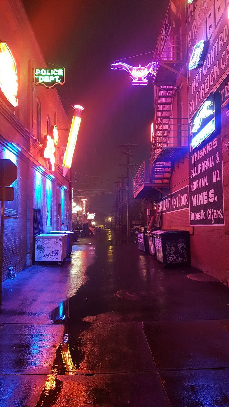 an empty city street at night with neon signs