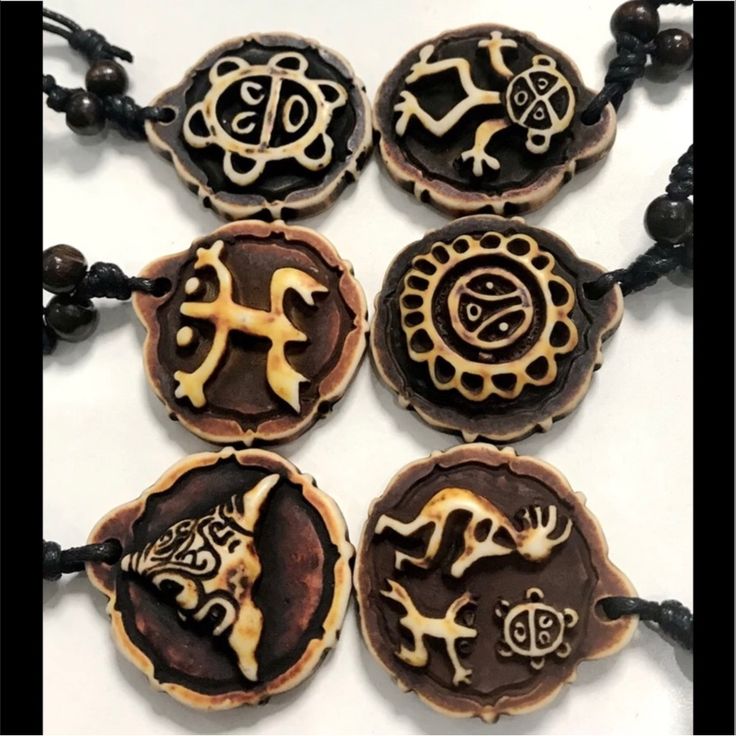 four necklaces with different designs on them sitting on top of a white countertop