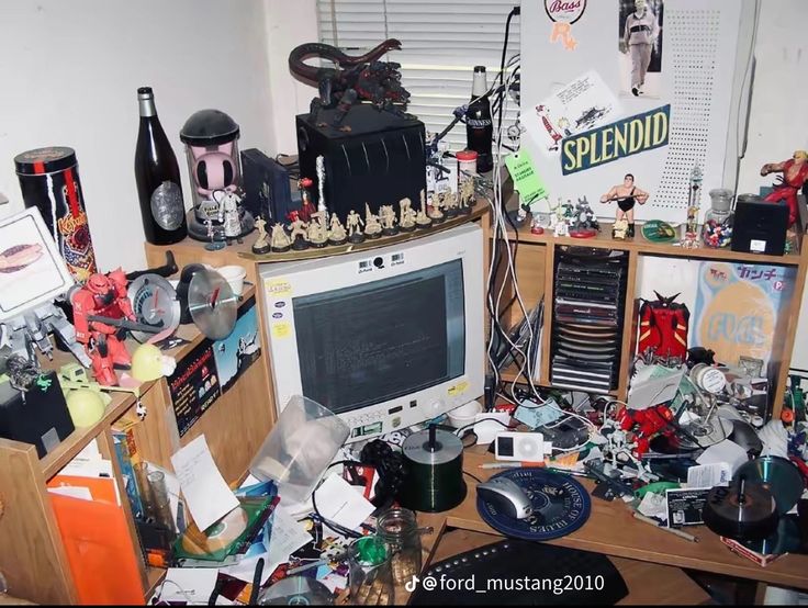 a cluttered desk with a computer monitor and many other items on top of it