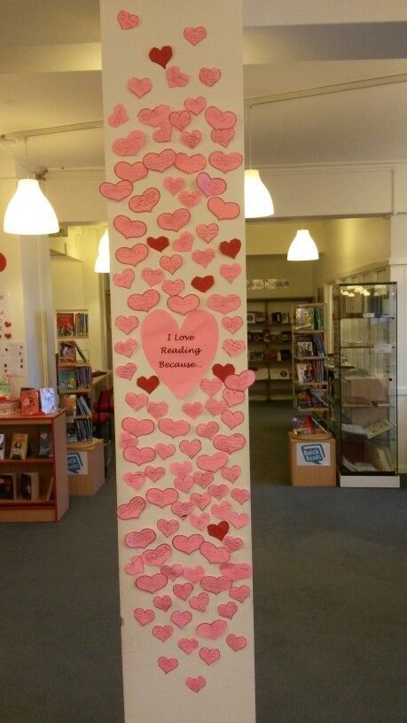 a tall white pole with pink hearts on it in an office building, next to a library filled with children's books