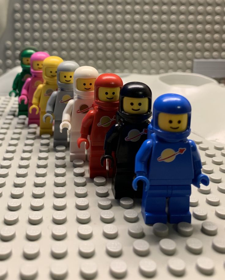 a row of lego minifigures sitting on top of a white table next to each other