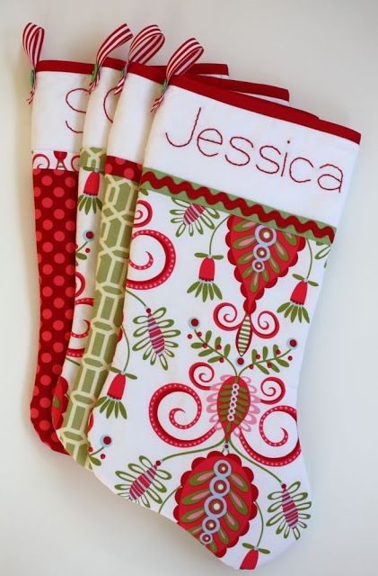 three christmas stockings with red and green designs are hanging on a white wall, one has a name written on it