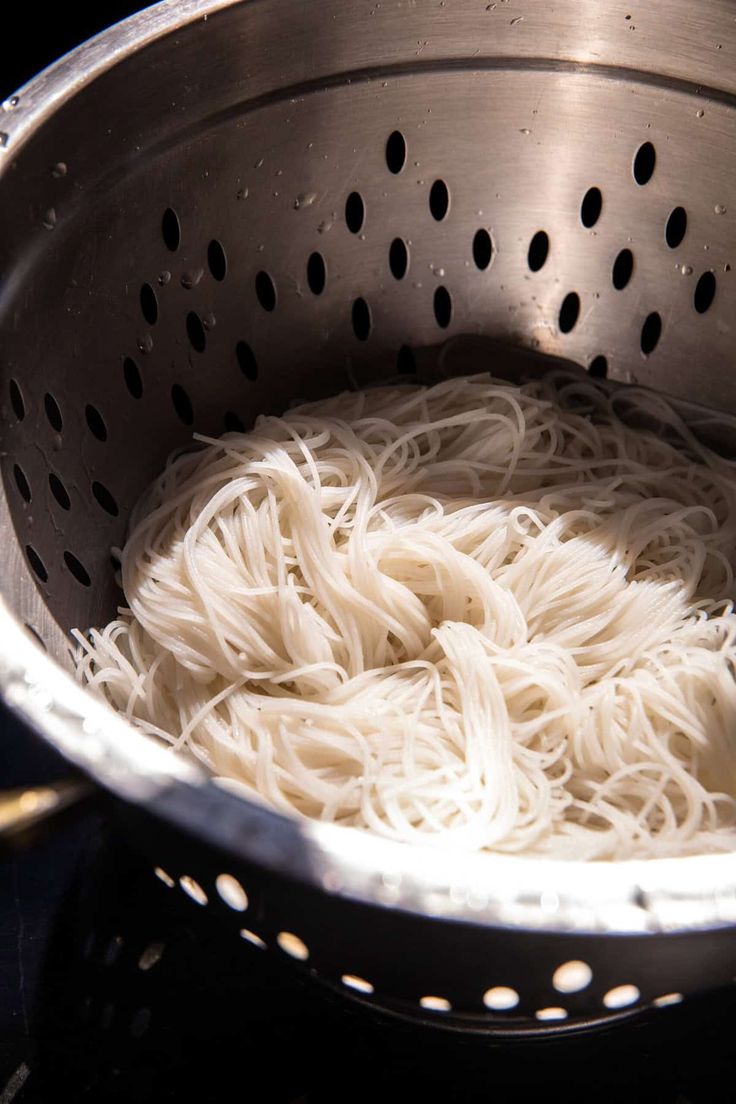 noodles are being cooked in a strainer on the stove