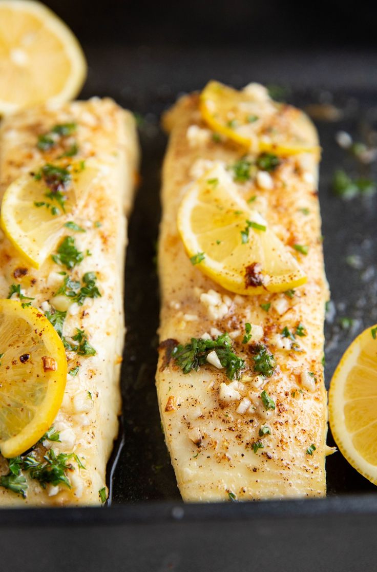 two fish fillets with lemon slices and parsley