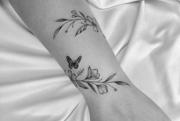 a black and white photo of a woman's arm with a butterfly tattoo on it