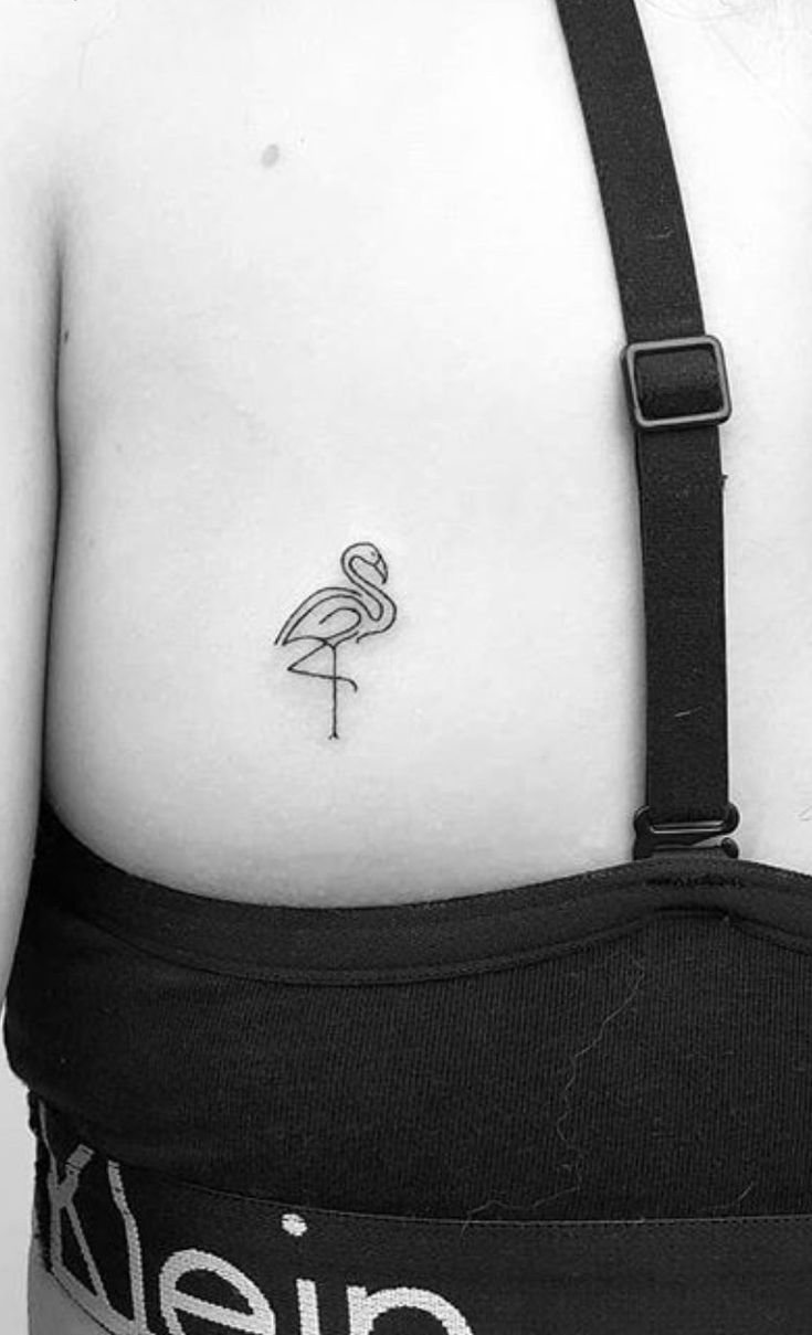 the back of a woman's stomach with a flamingo tattoo on her left side