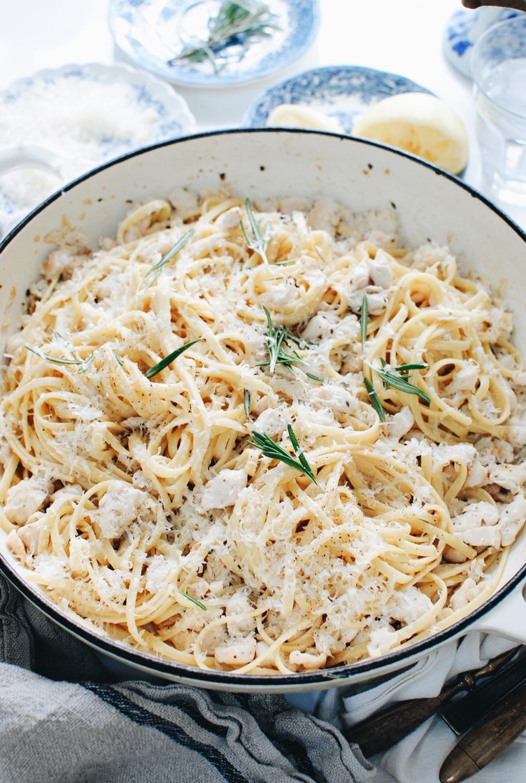 a pan filled with pasta and sauce on top of a table next to silverware