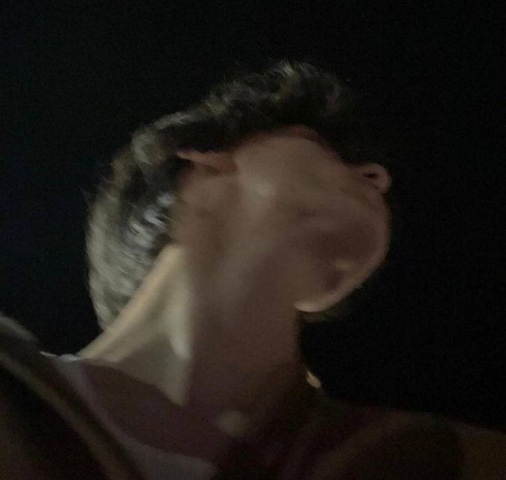 a blurry image of a man holding a cell phone up to his ear in the dark