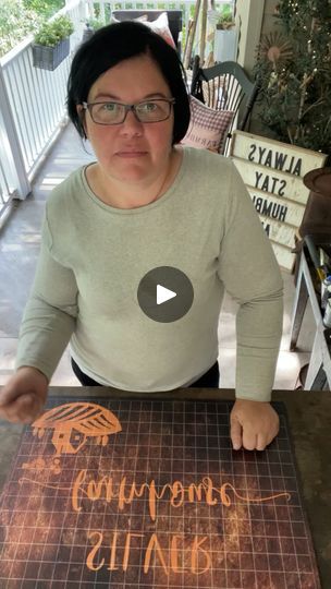 a woman sitting at a table with a sign in front of her that says,