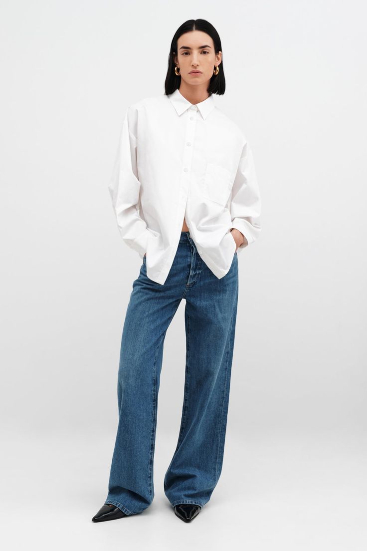 Relaxed and feminine, our oversized Raphaela Shirt is a true dream. Fashioned from crisp European poplin cotton, she's tailored with a sharp collar and a button front, which evens out her floaty shape and dolman sleeves. | Emily, in white, is 5'9.5" (177 cm) tall, wearing size XS. Approximately 29.5" (75 cm), measured from the shoulder to the bottom hem. Sleeve length approximately 22.5" (57.5 cm).100% European Poplin Cotton. Machine wash on delicate cycle or hand wash in cold water. Tumble dry White Oversized Shirt, Dolman Sleeve Shirt, Body Suit Outfits, Boyfriend Shirt, Winter Clothing, Black Bottoms, Oversized Shirt, Dolman Sleeve, Shirt Outfit