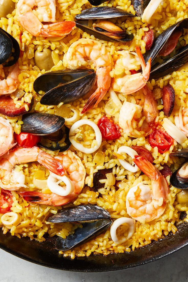 a skillet filled with shrimp, mussels and rice