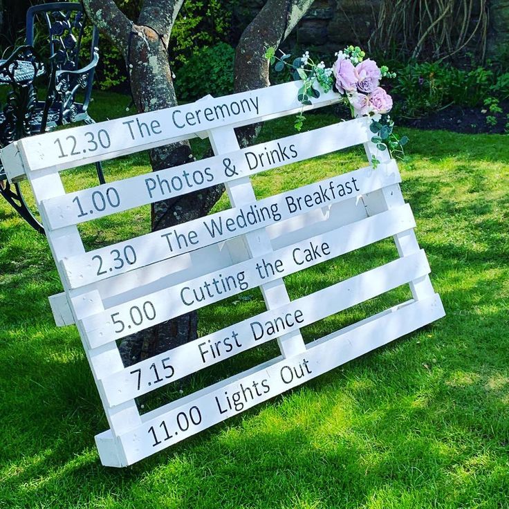 a wooden sign that is sitting in the grass with flowers on it's side