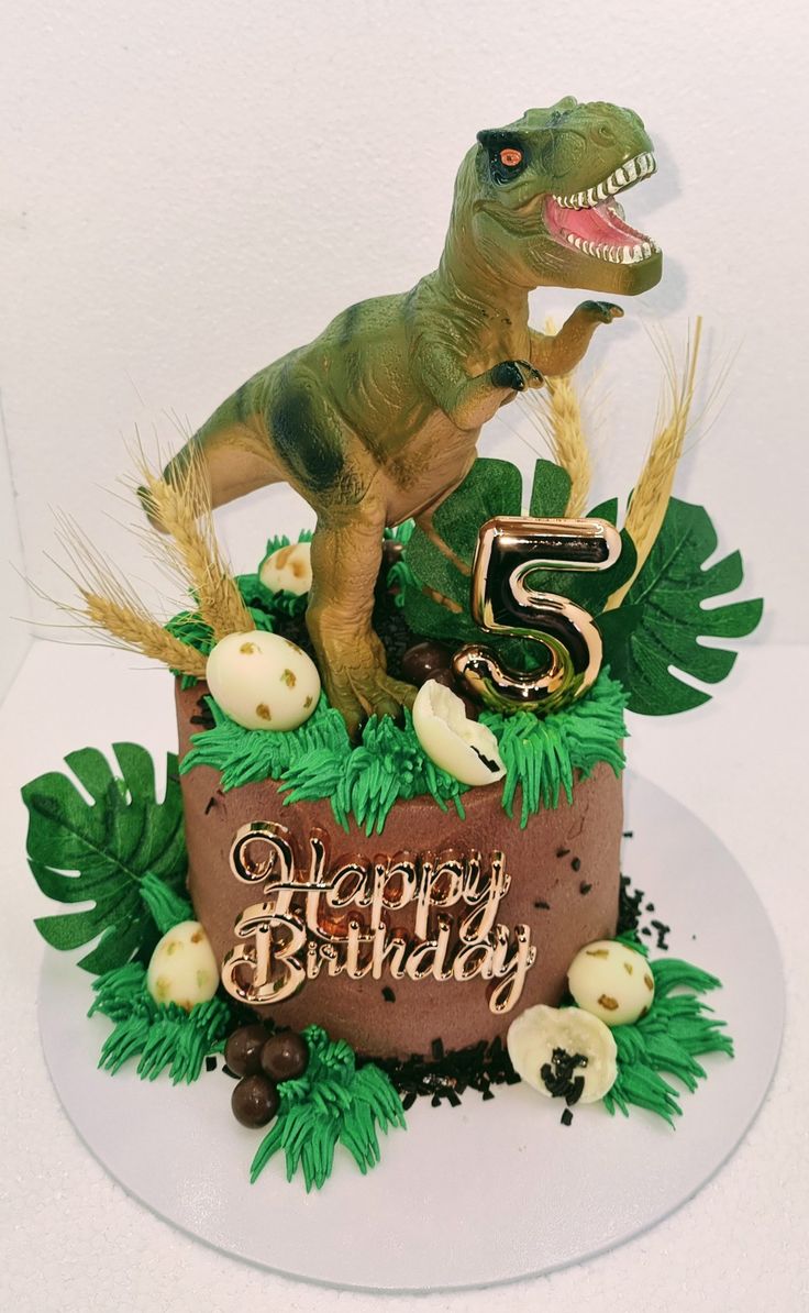 a dinosaur birthday cake with the number five on it