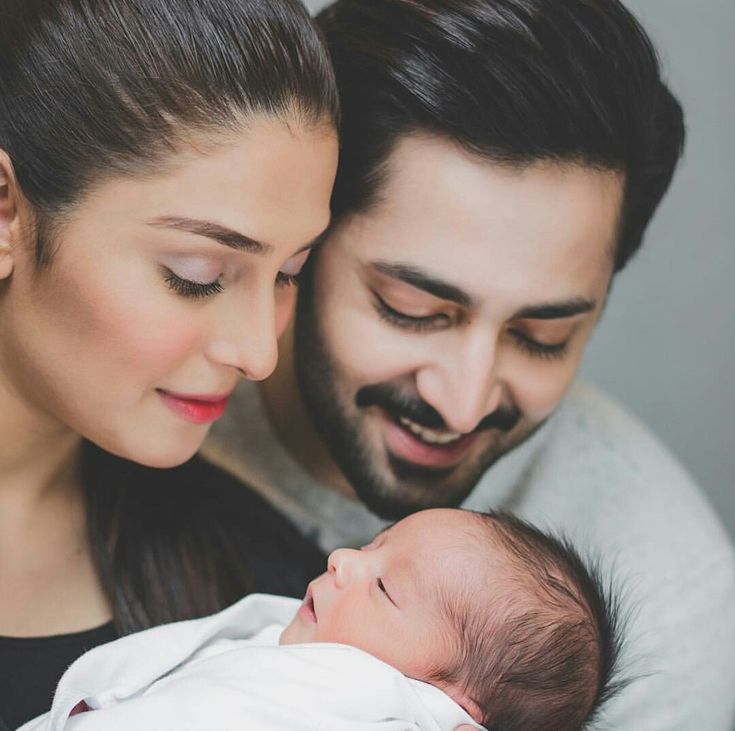 a man and woman holding a baby in their arms