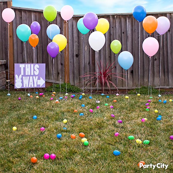 there are many balloons in the yard and one has a sign that says this way