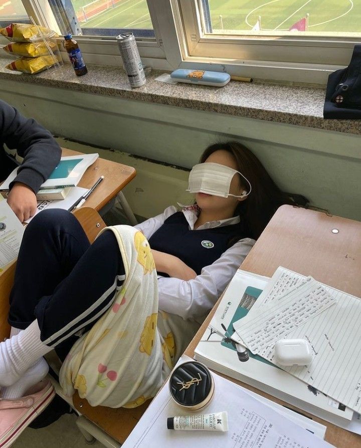 two people with blindfolds sitting at desks in front of a large window