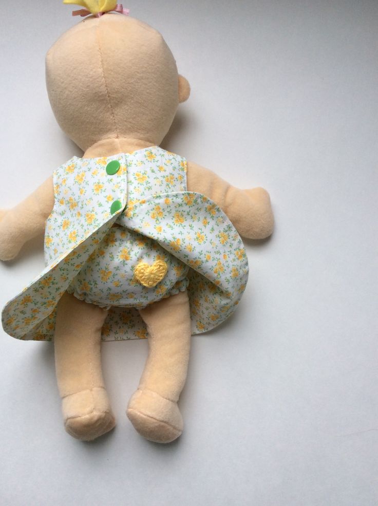 a stuffed toy doll with a dress on it's back laying on the ground