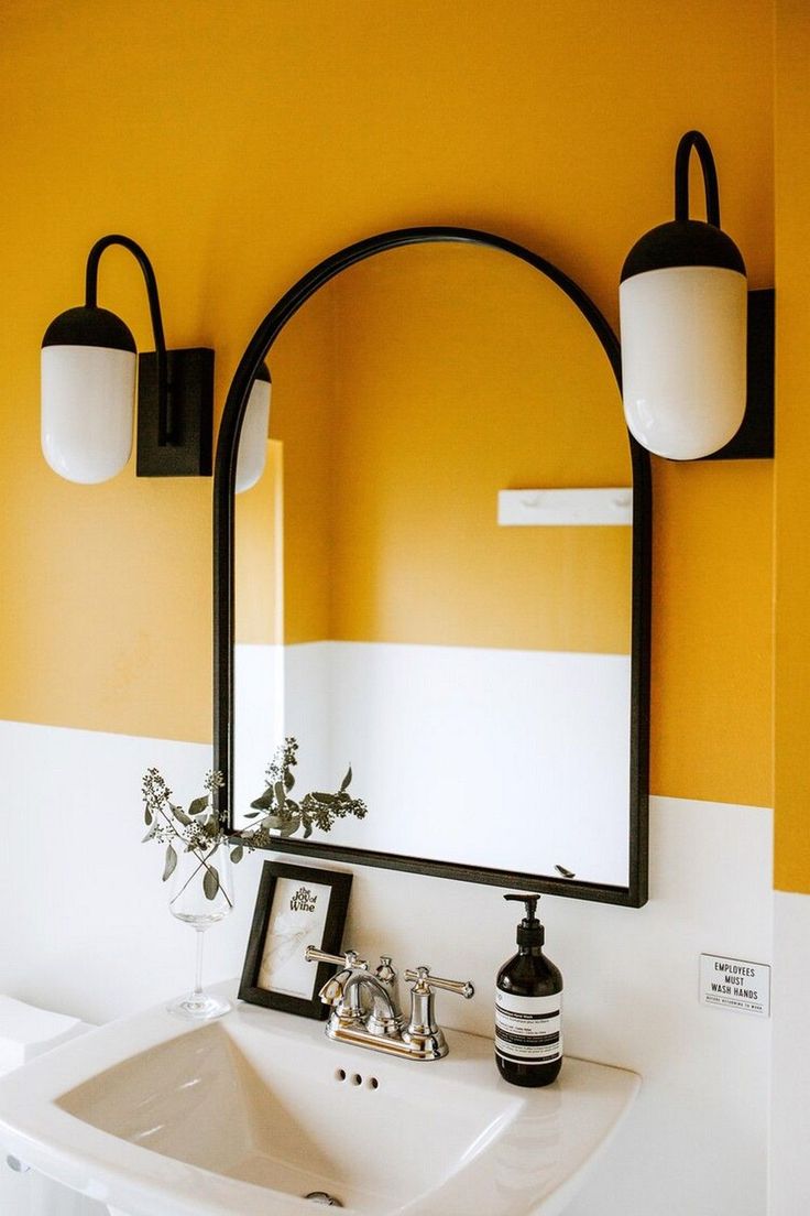 a bathroom sink sitting under a mirror next to a wall mounted faucet with lights on it