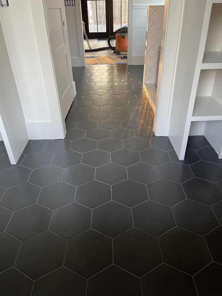 an empty room with white walls and black flooring is seen from the doorway to the hallway