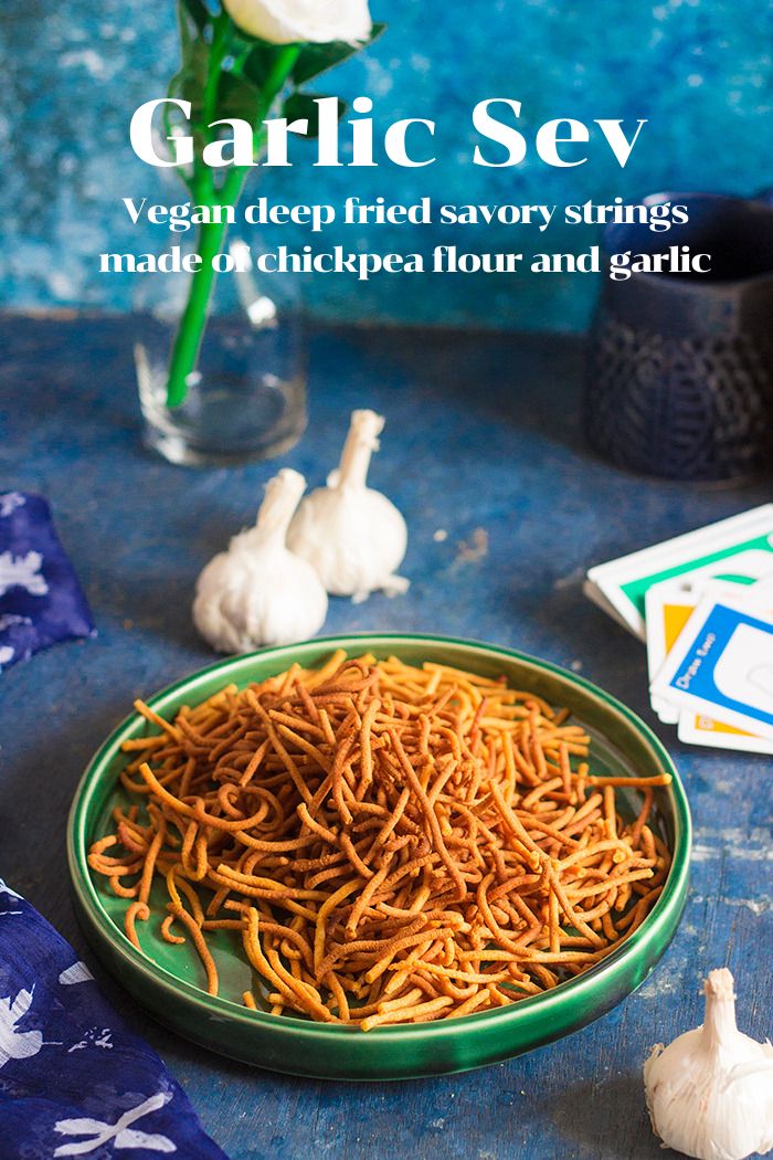 garlic sev in a green bowl on a blue table cloth next to flowers and cards