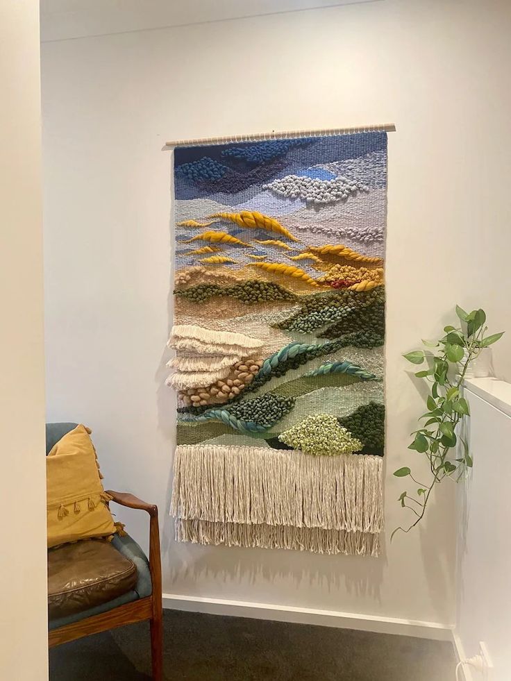 a tapestry hanging on the wall next to a chair with a plant in front of it