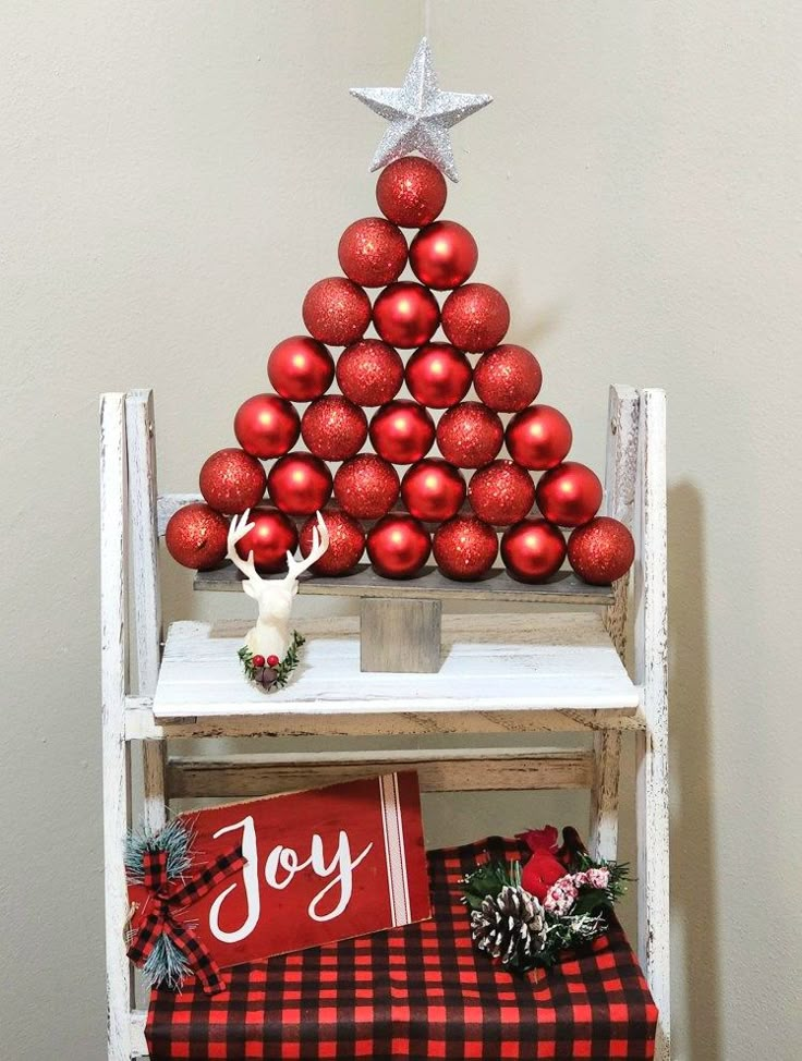 a christmas tree made out of red balls on top of a wooden shelf next to presents