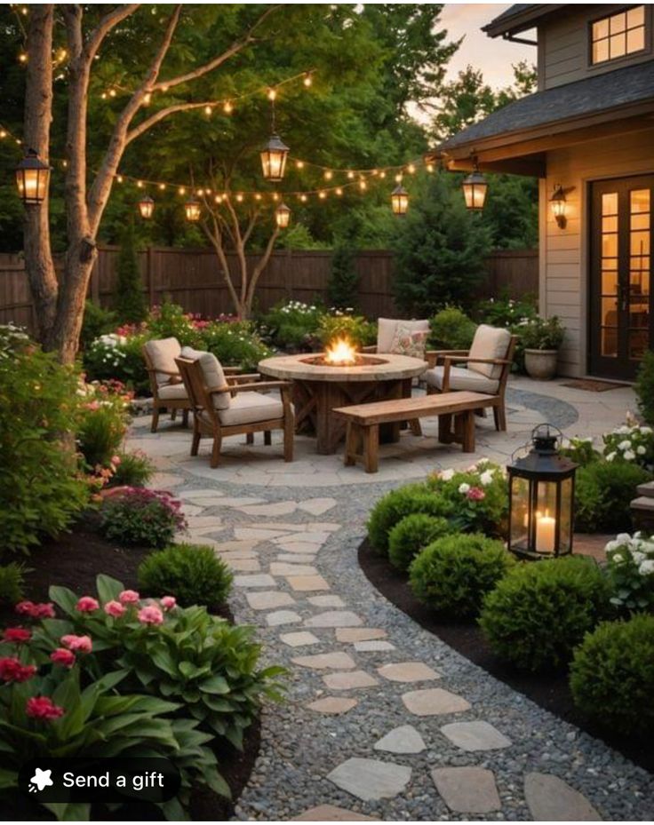 an outdoor dining area with lights strung over the table and chairs, surrounded by landscaping