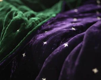 the bed is covered in purple and green sheets with white stars on them as if they were made out of fabric