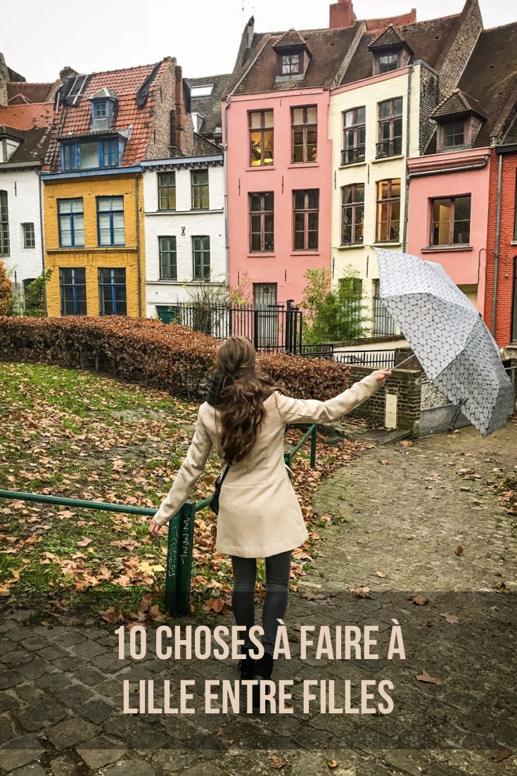 a woman holding an umbrella while walking down a path in front of colorful houses on a cloudy day